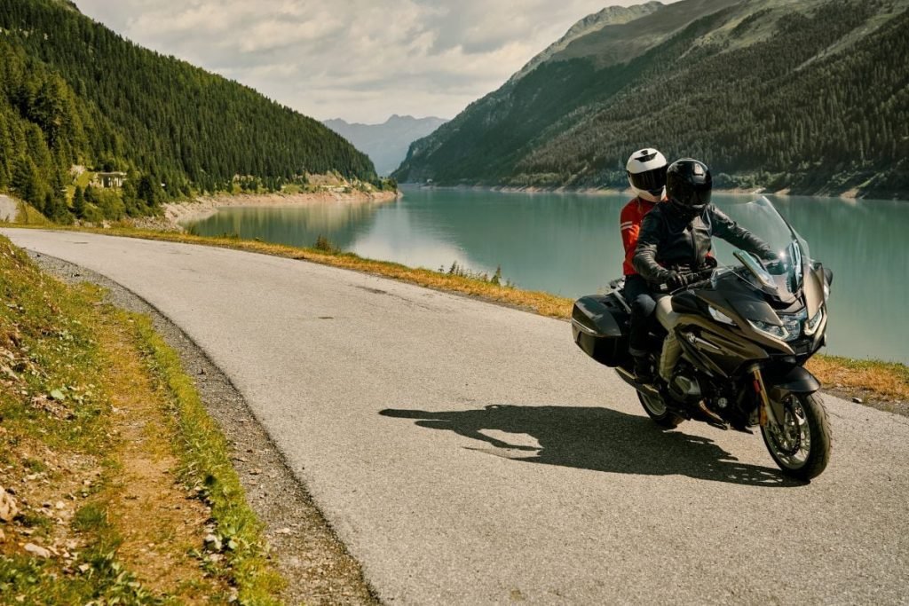 bmw rider and passenger passing lake - motorcycle pillion passenger