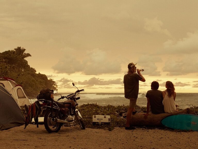 group of friends, motorcycle and tent at sunset