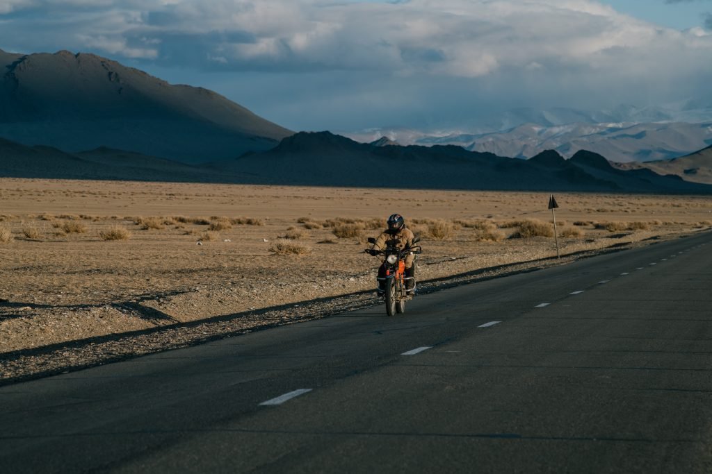 listening to music while riding a motorcycle - motorcyclist on desert road