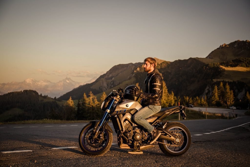 biker holding helmet in mountains