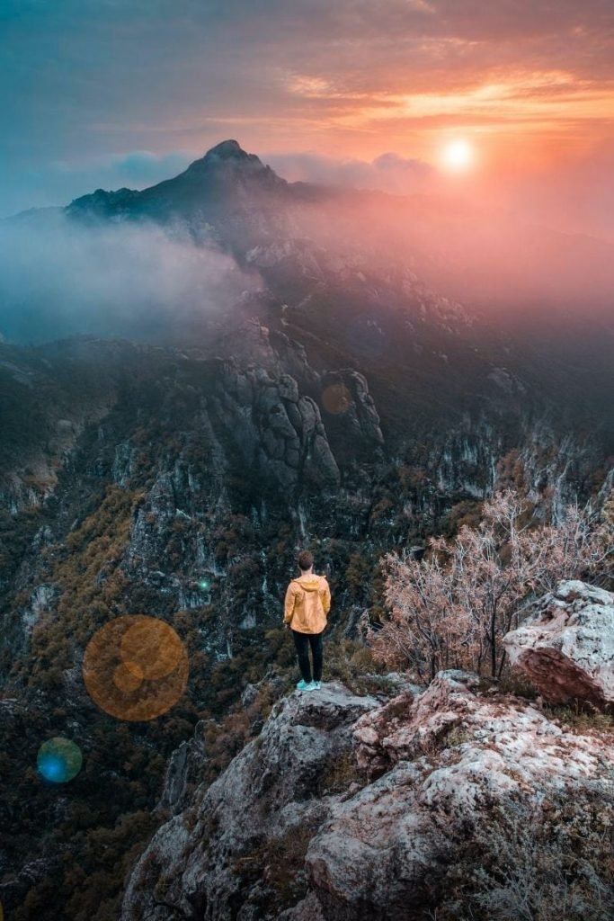 process image of man on cliff with mountains and sunrise