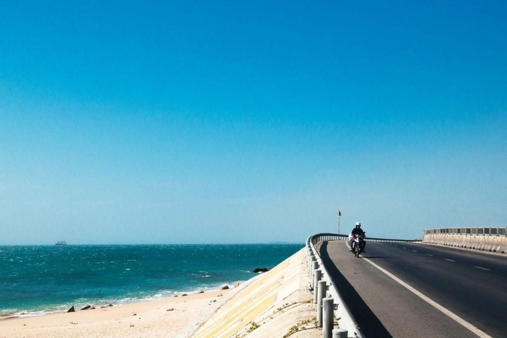 rider on coastal road with beach and sea