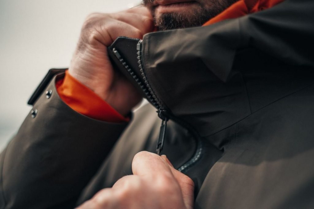 man zipping up winter coat
