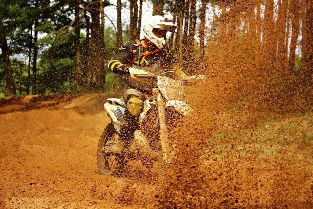 dirt bike spinning up mud and sand