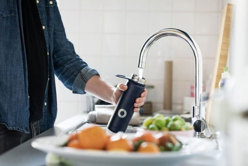 man filling up thermos flask from kitchen tap