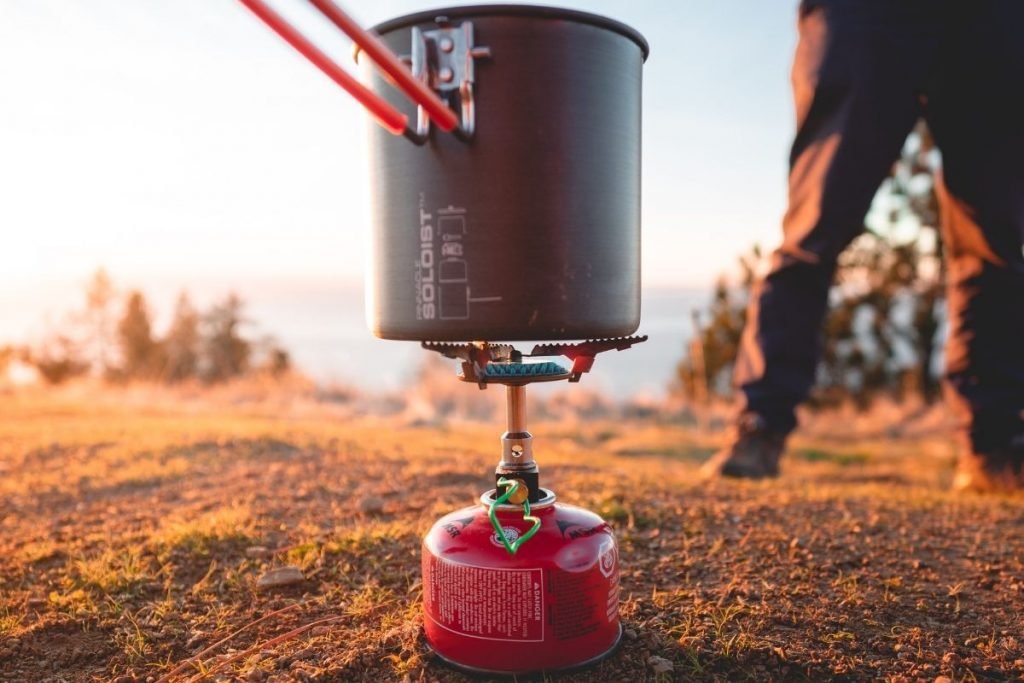 man cooking on camping stove