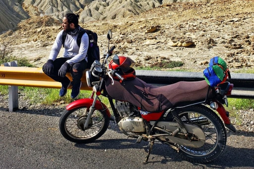 riding taking a break on a fence - motorcycle touring for beginners