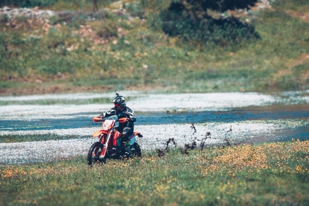 biker off-roading in grass with lake