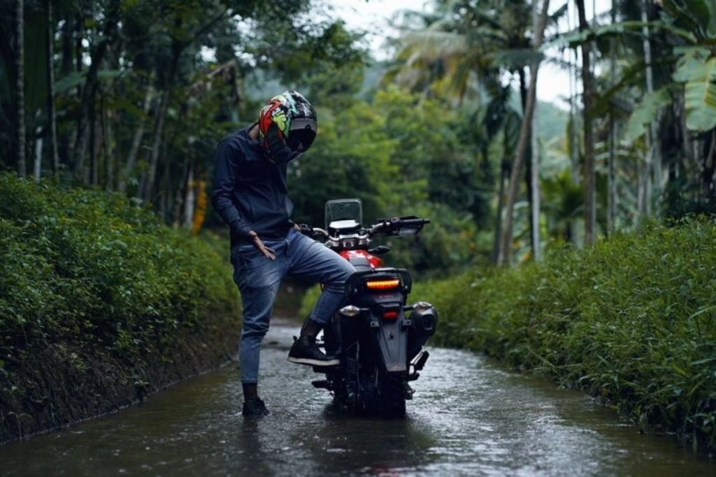motorcycle riding in the rain - rider in jeans in forest