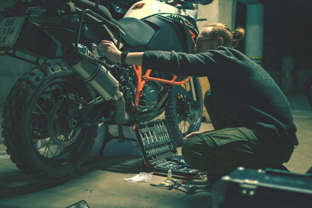 mechanic fitting parts on motorcycle - second-hand bike for touring